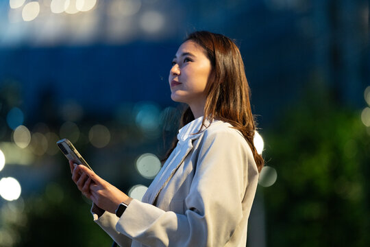スマホを片手に夜の雑踏にいる女性