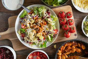 Tex mex barbecue chicken salad with kidney beans, avocado, cheese, lettuce, tomatoes, corn and...