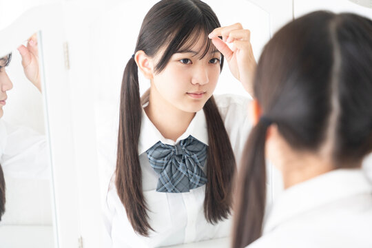 鏡を見ている制服姿の女子学生