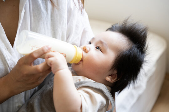 お母さんの腕の中でミルクを飲んでいる赤ちゃん