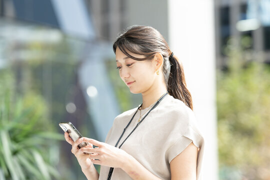 屋外でスマホを見ている女性のビジネスイメージ