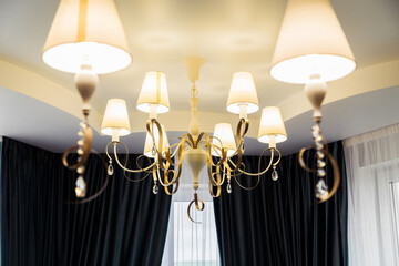 Elegant Chandelier in Modern Dining Room. Elegant chandelier with multiple lamps in a modern dining room with dark teal curtains.