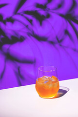 Orange alcoholic cocktail drink with gin, lemon juice and honey syrup, purple background