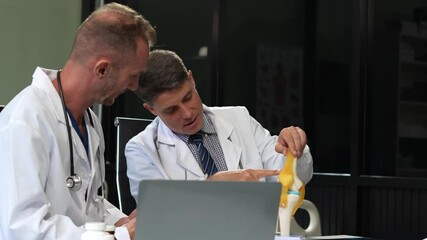 Doctors team are analyzing fracture knee model showing the process of osteoarthritis patients and knee arthroplasty. - Powered by Adobe