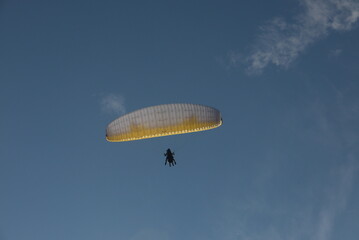 beautiful view of a paraglide flying in a clear blue sky at the sunset hour
