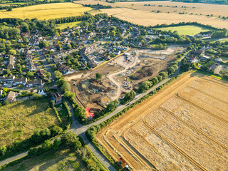 Harvested wheat and barley fields seen adjacent to an Essex village in the UK. A new housing development can be seen adjacent to the existing village.