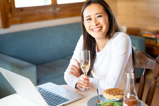 ノートパソコンを前にリモート飲み会をしている女性
