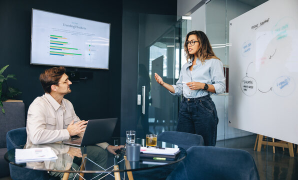 Business woman delivering a marketing presentation to her partner and colleague in an office - Powered by Adobe