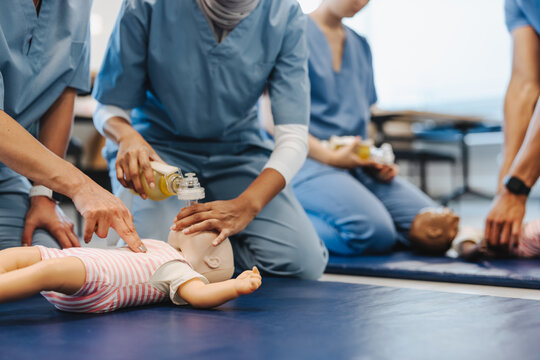 Female medical students practicing CPR on baby manikin during medical training