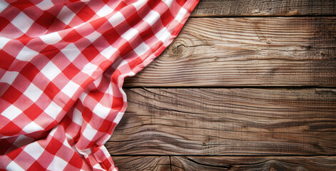 Red and white checkered tablecloth on a wooden background with space for text or design, top view of a picnic cloth over an old brown wood texture