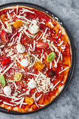 margherita pizza with cherry tomatoes before going in the oven