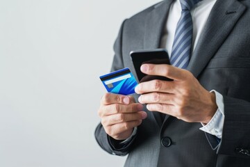 Businessman holding a credit card and smartphone isolated on a white background with copy space.