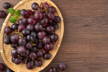 Delicious bunch of grapes fruit in a plate on wooden table background.