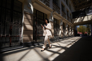 Obraz premium business woman in a suit works during rush hour. a young girl hurries to a meeting. young entrepreneur. freelancer. successful business