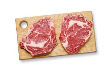 Raw marbled ribeye steaks on board