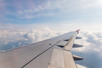Fototapeta na wymiar View from the airplane window at a beautiful cloudy sky and the airplane wing