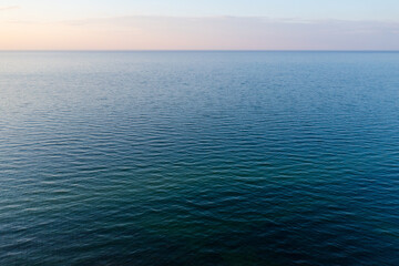 Tranquil ocean scene at dusk featuring calm water and a pastel-colored sky, evoking a sense of...