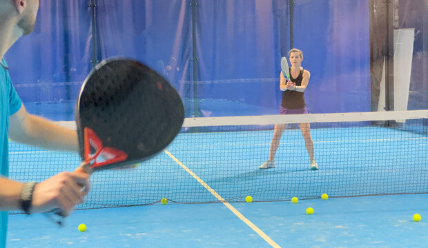 Empowering padel tennis training as a coach skillfully instructs a young woman on the court, fostering skill development and a positive learning environment