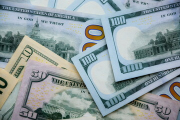 Big amount of US dollar bills in different nominations on table. Many dollar banknotes under natural light