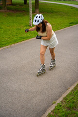 Roller skater woman in park rollerblading on inline skates. Outdoor activities. Summer roller...