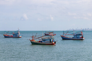 Fototapeta premium Fishing boat floating on the sea with city on background.