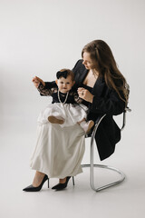 A happy woman is holding a smiling baby girl in black and white outerwear