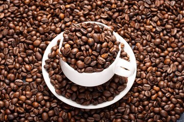 close-up of white cup with white saucer full of roasted coffee beans, copy space