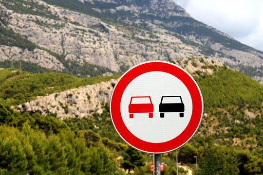 Sign - overtaking is prohibited on the side of a beautiful mountain road. Passenger cars are prohibited from overtaking, prohibition road sign