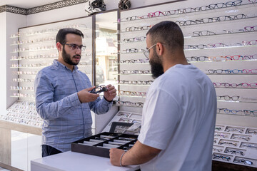 Male selecting the best eyeglasses, also selecting sunglasses whihc is clips eyeglasses