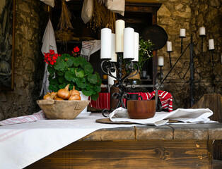 Rustic table setting with onions, candles, and pottery is ready for a meal