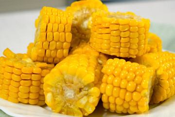 Close-up pieces of baked fresh sweet corn on plate cooked on kitchen at home. Prepare cook bake dish. Cuisine culinary nutrition domestic food recipe ingredients, organic vegetable.