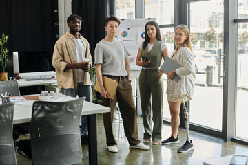 Four people, including one with a prosthetic leg, stand together in a modern office.