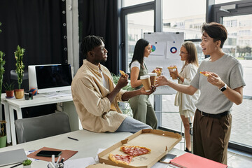 Four young colleagues take a break from work, enjoying pizza and coffee in a modern office