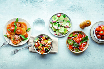 Fresh vegetarian salads, overhead flat lay shot of an assortment. Variety of plates and bowls with green vegetables. Healthy food, with a drink