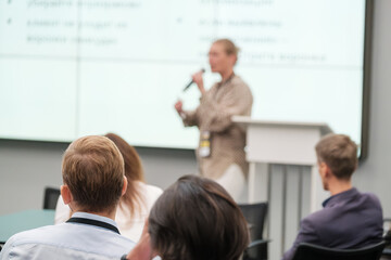 Fototapeta premium Speaker giving presentation at business conference while audience listens attentively. Professional development and networking