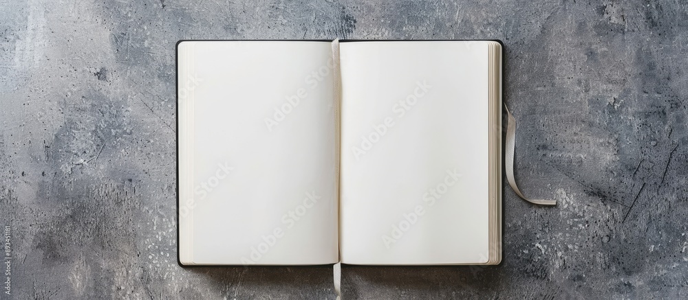Poster Real photograph featuring a design concept with a top view of an open white notebook including a ribbon bookmark set against a grey background providing copy space image