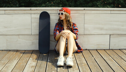 Stylish young woman with skateboard in casual clothes, modern teenage girl posing in the city