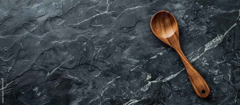 Poster handcrafted wooden spoon displayed on a sleek black marble surface with copy space image