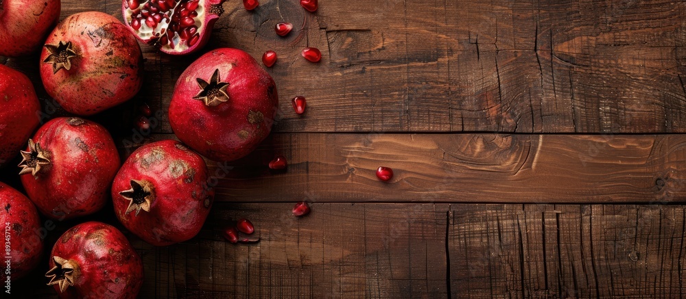 Poster a flat lay display with fresh pomegranates and room for text on a wooden surface. with copy space im