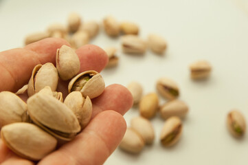 Shelled and unshelled pistachios on white background,hands holding some pistachios