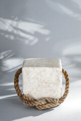 Marble stone cube stand pedestal with copy space for products. White wall with sunlight backhround.