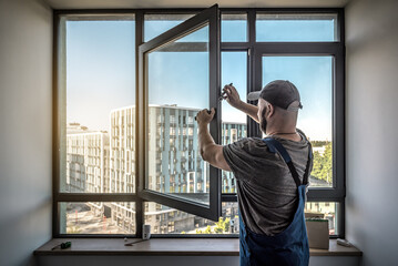Worker adjusting dark pvc plastic window indoors. worker using pliers to repair window