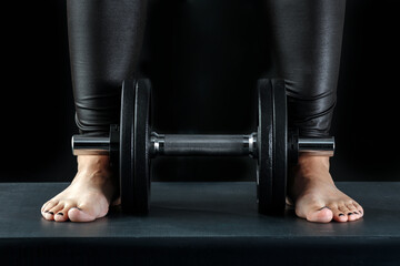 Dumbbells and weights. Workout in the gym. Only woman's parts of the body visible. Black background.