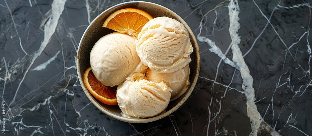 Poster Orange citrus ice cream in a bowl on a stone backdrop with room for text or other elements in the image A chilled treat for the summer viewed from above in a flat lay composition