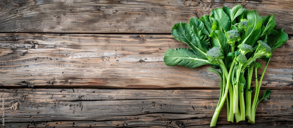 Poster Green fresh Gai lan Chinese broccoli on a wooden plank viewed from the top with a clear background suitable for text or other elements in the copy space image