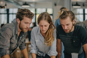 Obraz premium Three people gathered around discussing ideas in a bright modern workspace, engaging in creative brainstorming and teamwork to solve problems or plan projects efficiently.