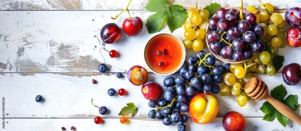 Aufkleber top view of fresh grapes blueberries plums and honey on a white tabletop with a wooden background cr