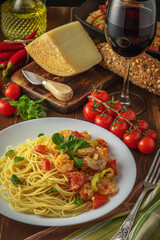 Spaghetti with shrimps, cherry tomatoes and spices on wooden background. Food background.