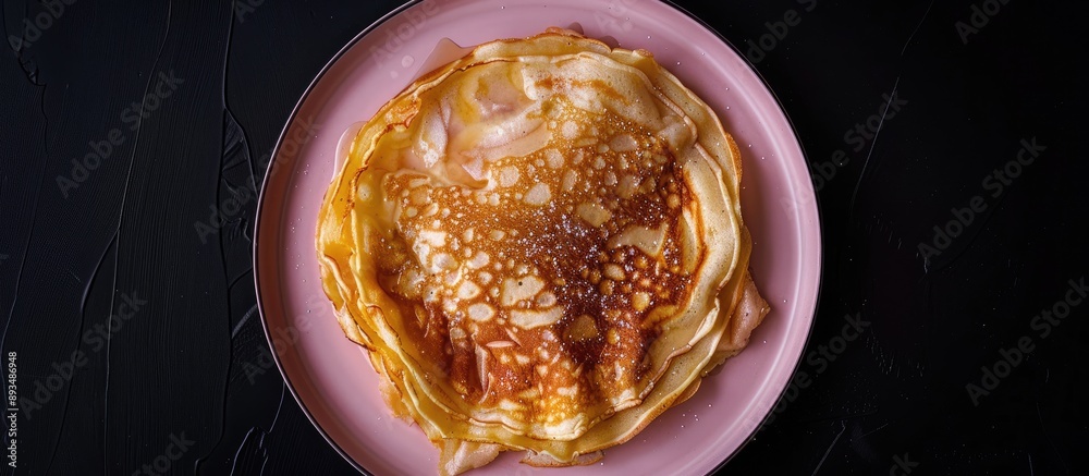 Poster top view of a homemade apple dutch pannekoek pancake served on a pink plate against a black backdrop