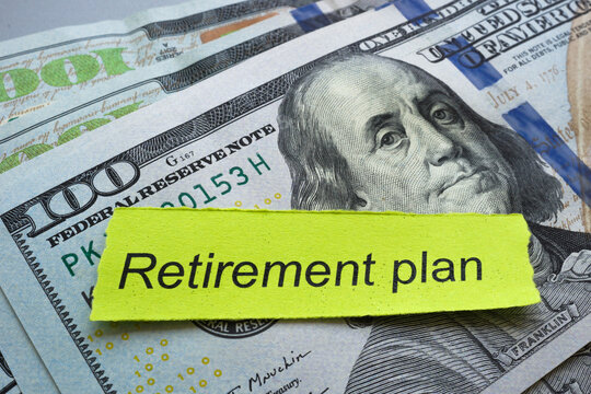 Stack of money with piece of paper and words retirement plan.